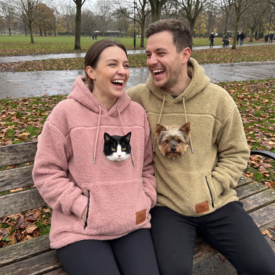 Couple walking in an autumn park wearing Pawket hoodies, one with a cat and one with a Yorkie